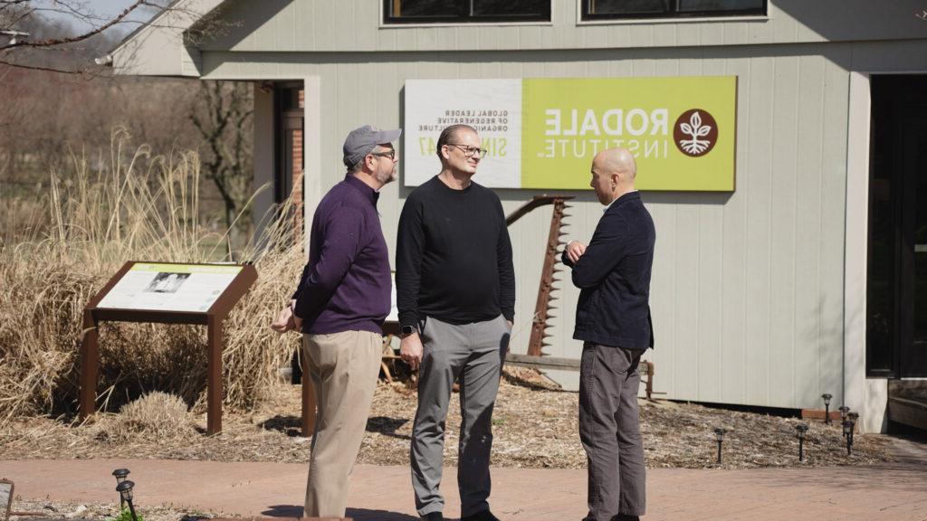 People near barn with sign talking