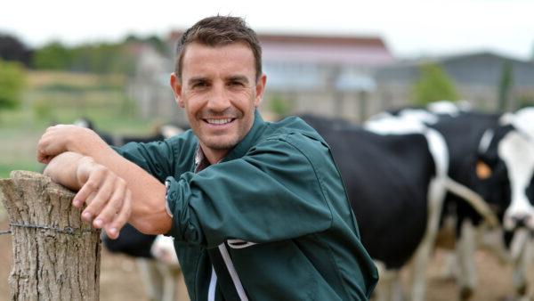 Herdsman standing in front of cattle in farm